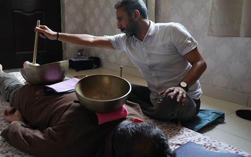 Sound healing practitioner playing a singing bowl during a session